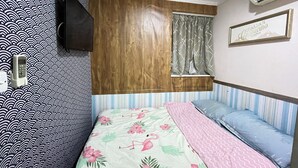 A bedroom with a bed, a TV mounted on the wall, a window with curtains, and an air conditioning unit. - Cindy Hostel (Kowloon)