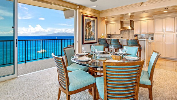 Zona pranzo con vista sull'oceano, cucina con mobili in legno e un balcone con ringhiera.