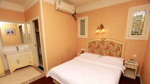 A bedroom with a large bed, a bedside table, a nightstand, a mirror, a wardrobe, and a window with a view. - Jiali Inn Tidu Branch (Chengdu)