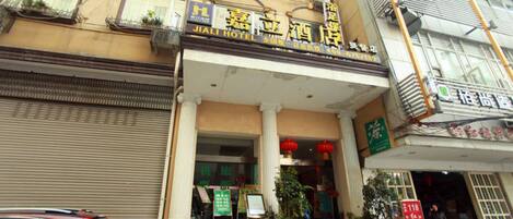 A hotel entrance with a sign reading "JIALI HOTEL" and a staircase leading up to the entrance.