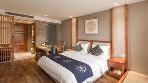 Ein Hotelzimmer mit einem großen Bett, einem Holzkopfende und einem kleinen Schreibtisch mit Stuhl.
