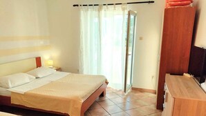 Una habitación de hotel con cama, escritorio, televisor y armario.