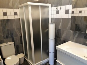 Une salle de bain moderne dotée d’une douche à parois de verre, de toilettes et d’une baignoire.