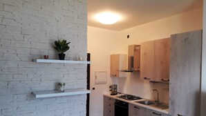 Une cuisine moderne avec des murs en briques blanches, des armoires en bois et des étagères intégrées.
