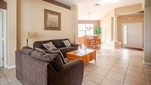 A spacious lobby with a brown sofa, a wooden coffee table, and a dining area with chairs and a table.