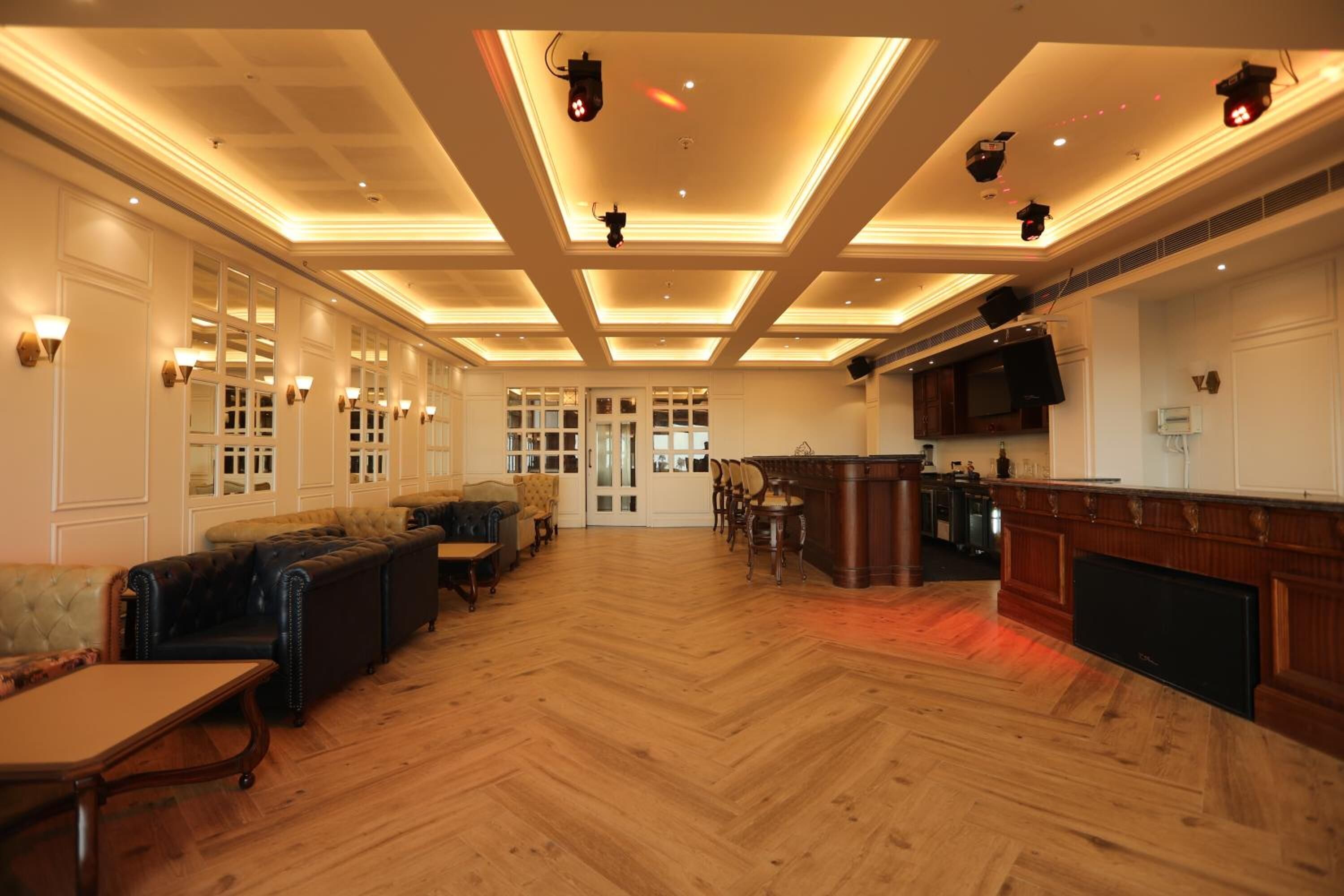 Un hall d’hôtel spacieux, doté d’un plancher en bois, de canapés en cuir, d’un bar et d’un grand écran de télévision.