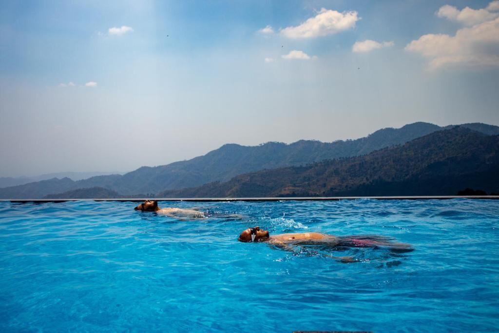 A pool with clear blue water and a mountainous landscape in the background.
