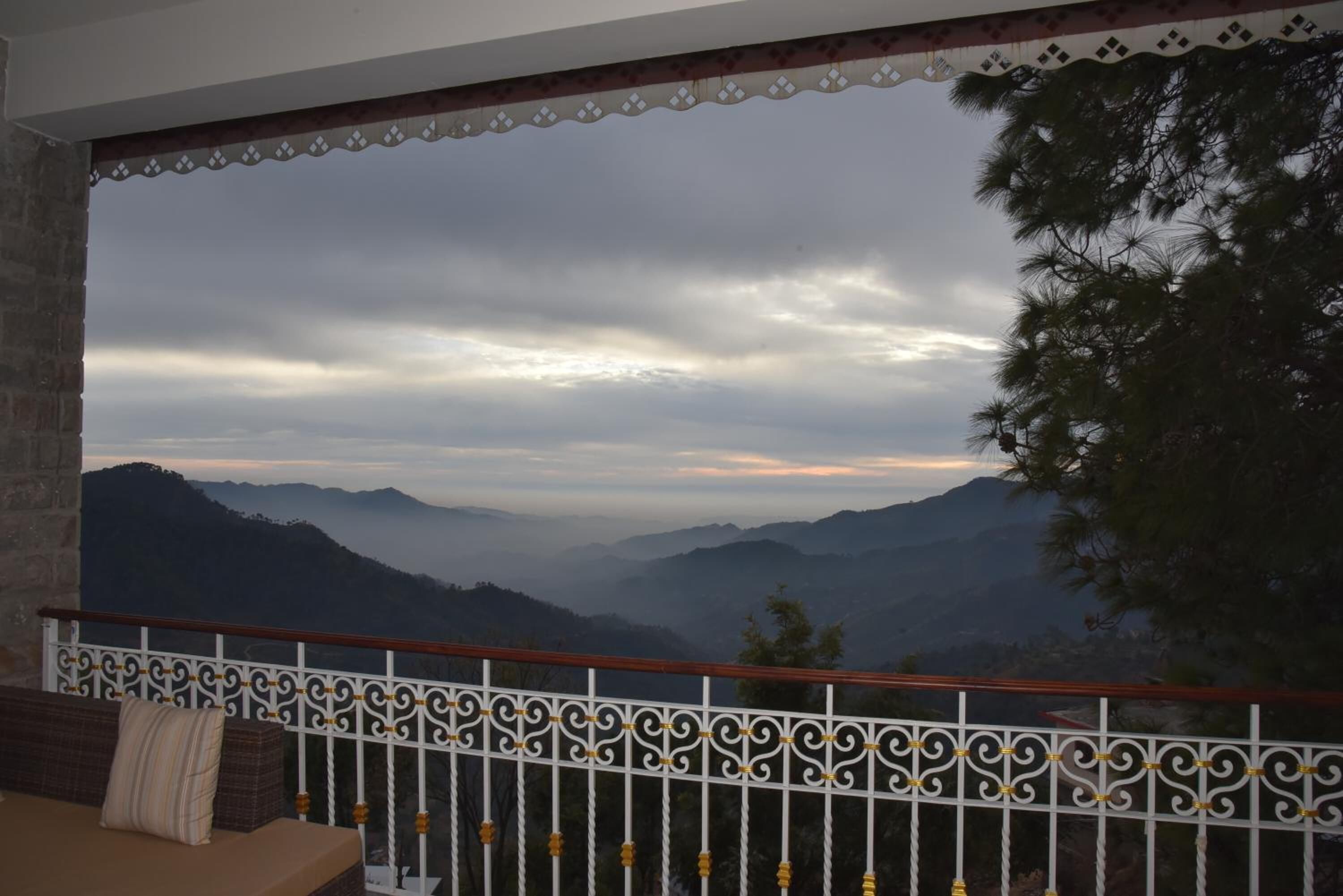Un balcón con barandilla blanca decorativa, con vistas a un paisaje montañoso.