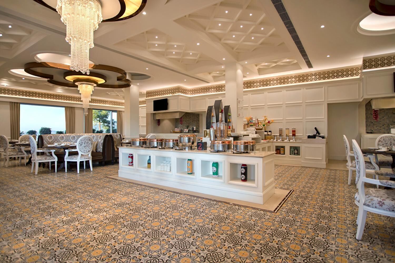 Un comedor amplio con una barra de buffet central, baldosas de diseño y elegantes lámparas de araña.