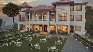 A large, multi-story hotel with a spacious outdoor patio area featuring numerous tables and chairs, a well-maintained lawn, and a scenic mountain backdrop. - Fortune Select Forest Hill, Kasauli - Member ITC Hotels' Group (Solan)