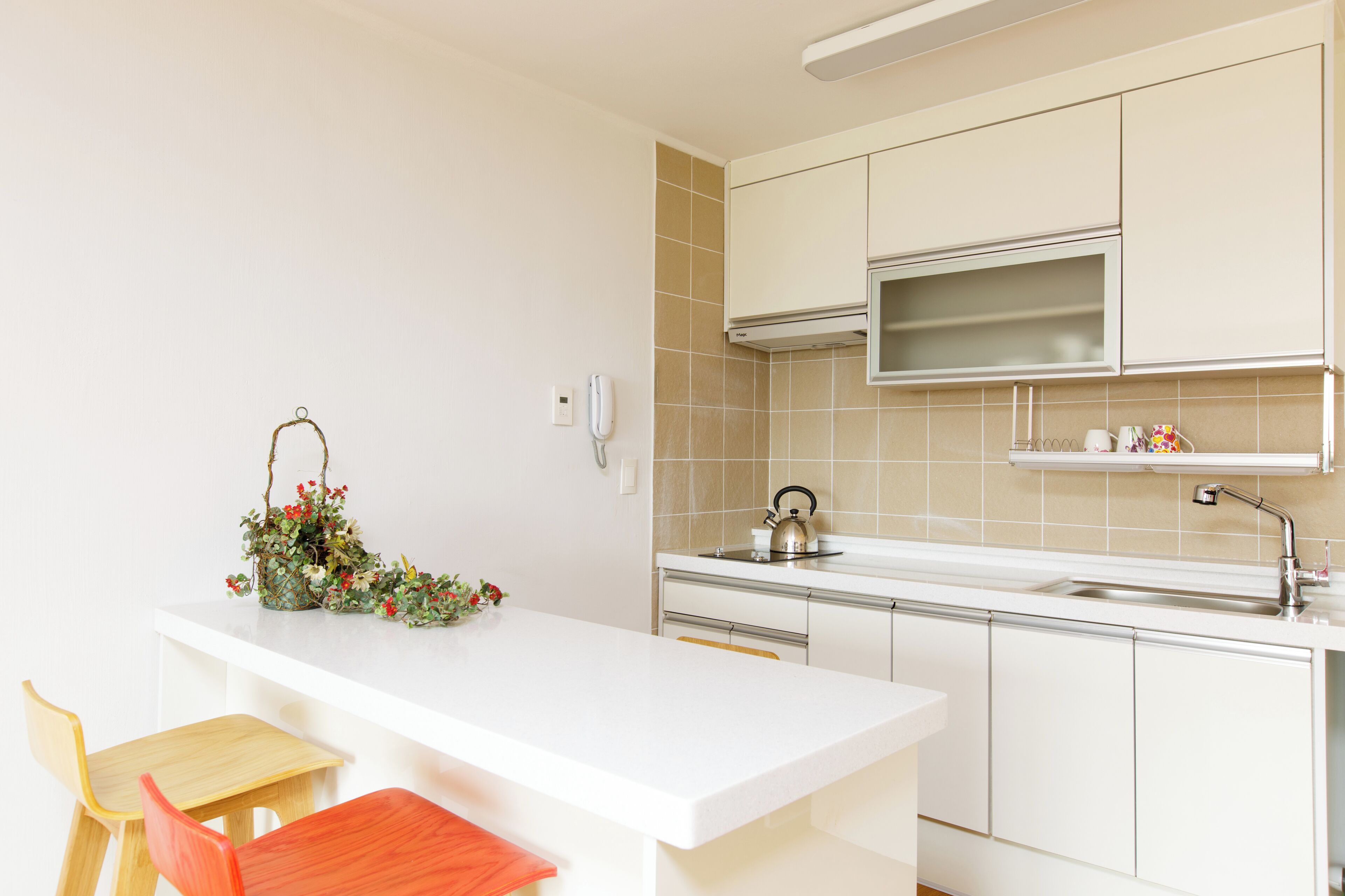 A modern kitchen with white cabinetry, a built-in microwave, and a kettle on the countertop.