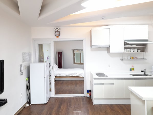 Una habitación de hotel compacta con kitchenette, una cama, un espejo y un baño pequeño.