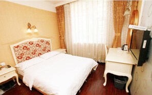 A hotel room with a bed, bedside table, lamp, and a small desk with a mirror. - Jiali Inn Tianfu Branch (Chengdu)