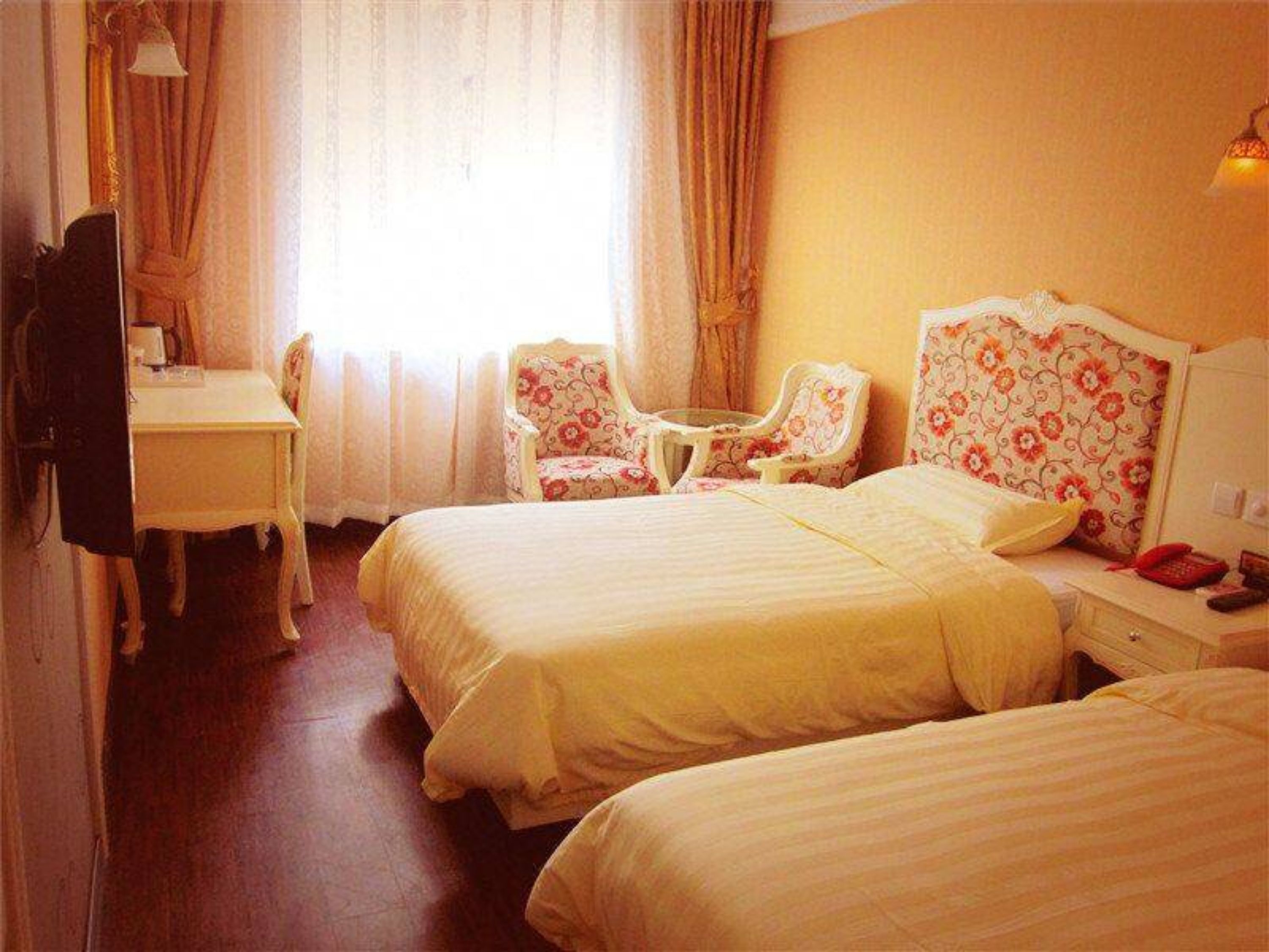 Ein Hotelzimmer mit zwei Betten, einem Schreibtisch, einem Stuhl und einem kleinen Tisch.