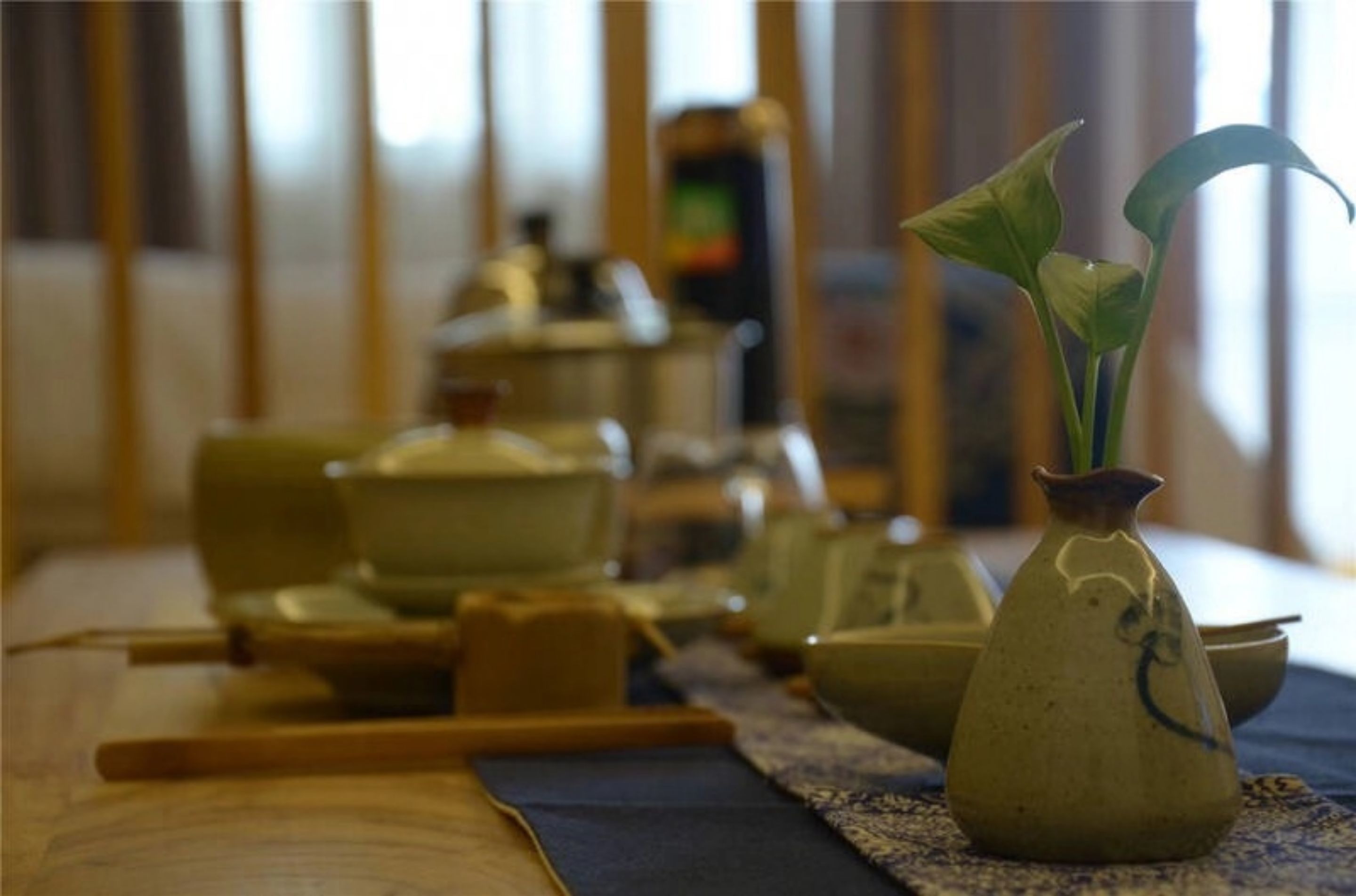 A traditional Japanese tea ceremony setup with a tea bowl, a ceramic pitcher, and a bamboo whisk on a tatami mat.