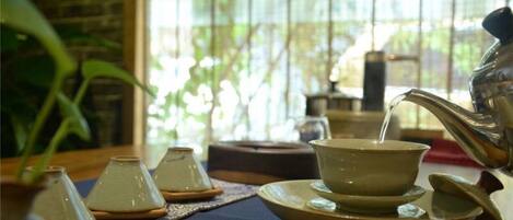 A traditional tea set on a table with a window in the background.