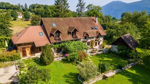 Una grande casa a due piani con tetto spiovente, fondamenta in pietra e un giardino curato.