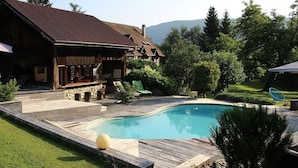 Una cabina di legno con piscina, circondata da un solarium e rigogliosa vegetazione.