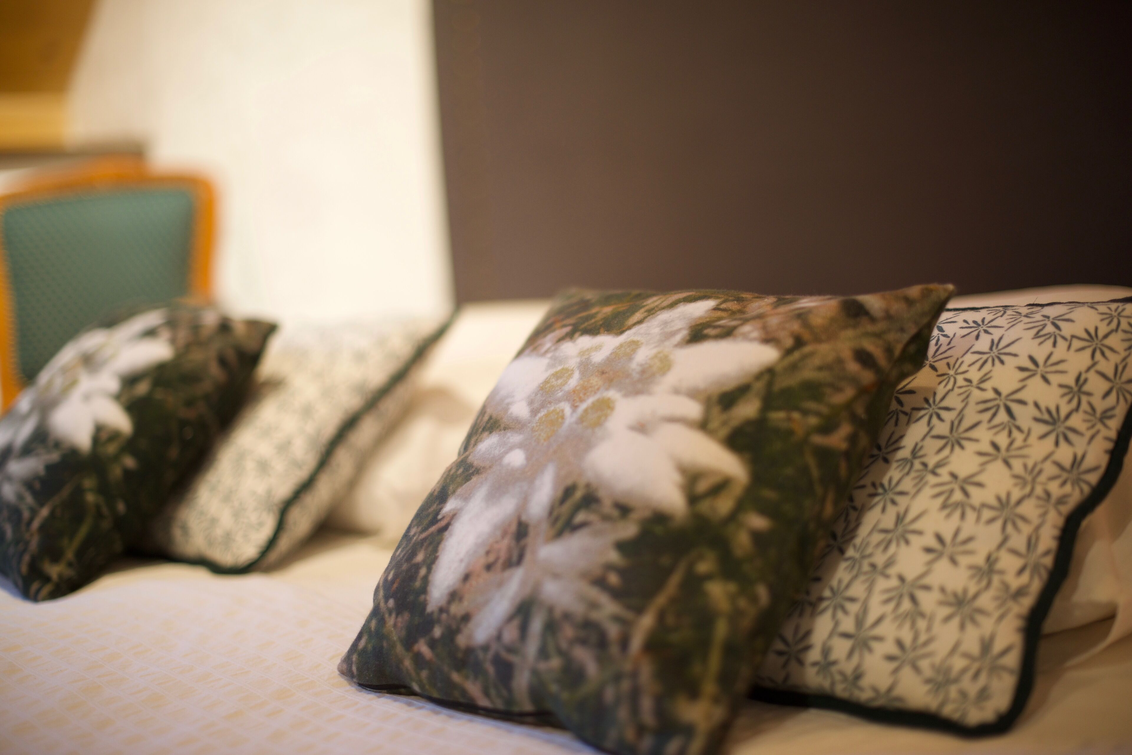 A bed with three pillows, each with different patterns.