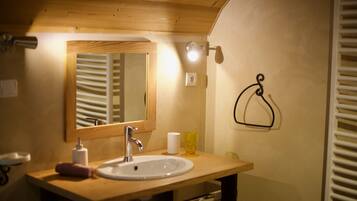 Un bagno con un mobile bagno in legno, un lavandino bianco, uno specchio, un asciugamano e un bicchiere.
