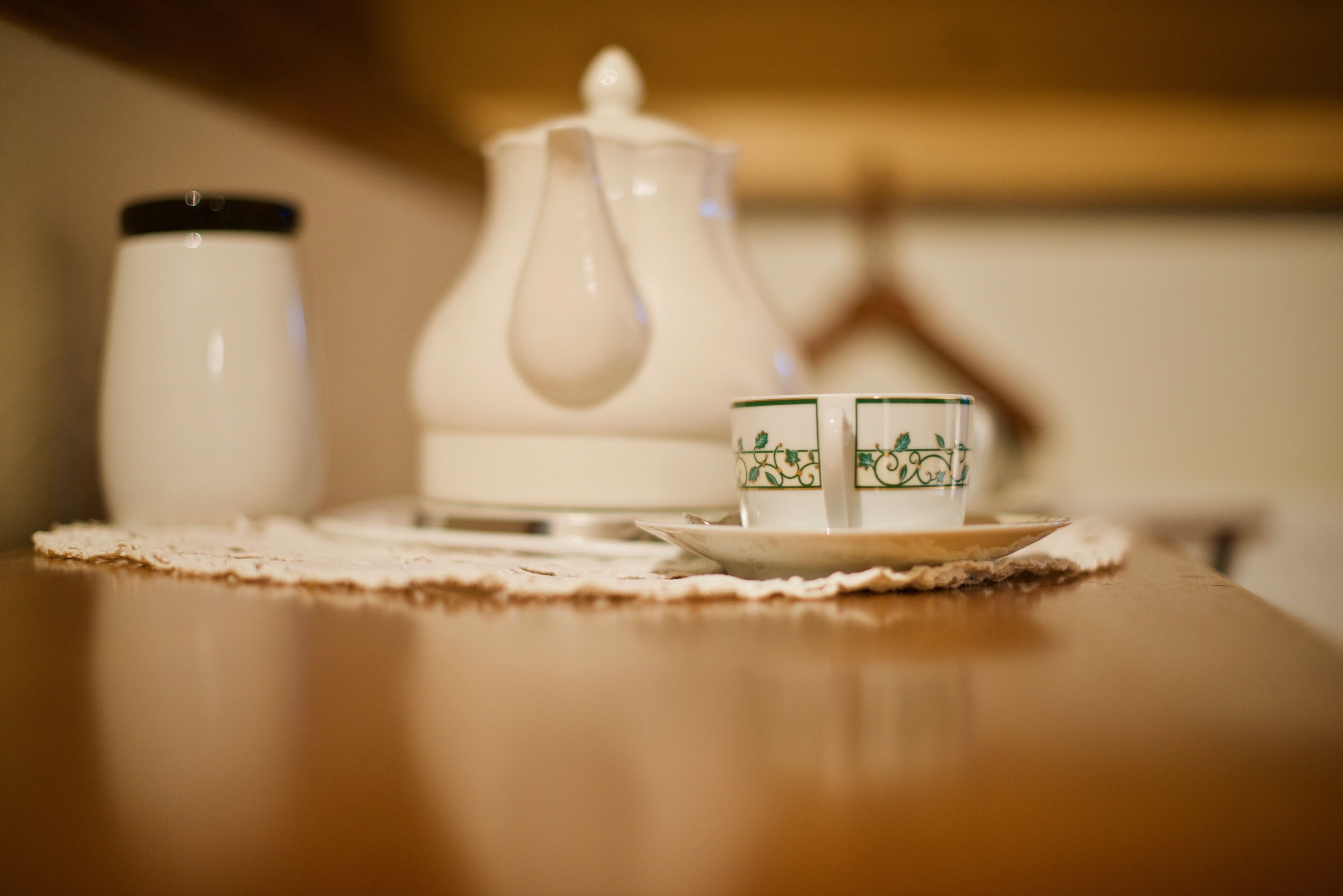 A table with a teapot, two cups, and a saucer on a placemat.