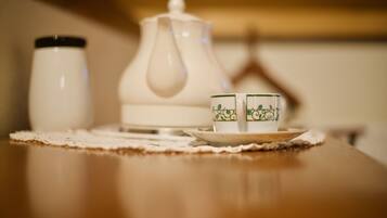 A table with a teapot, two cups, and a saucer on a placemat.