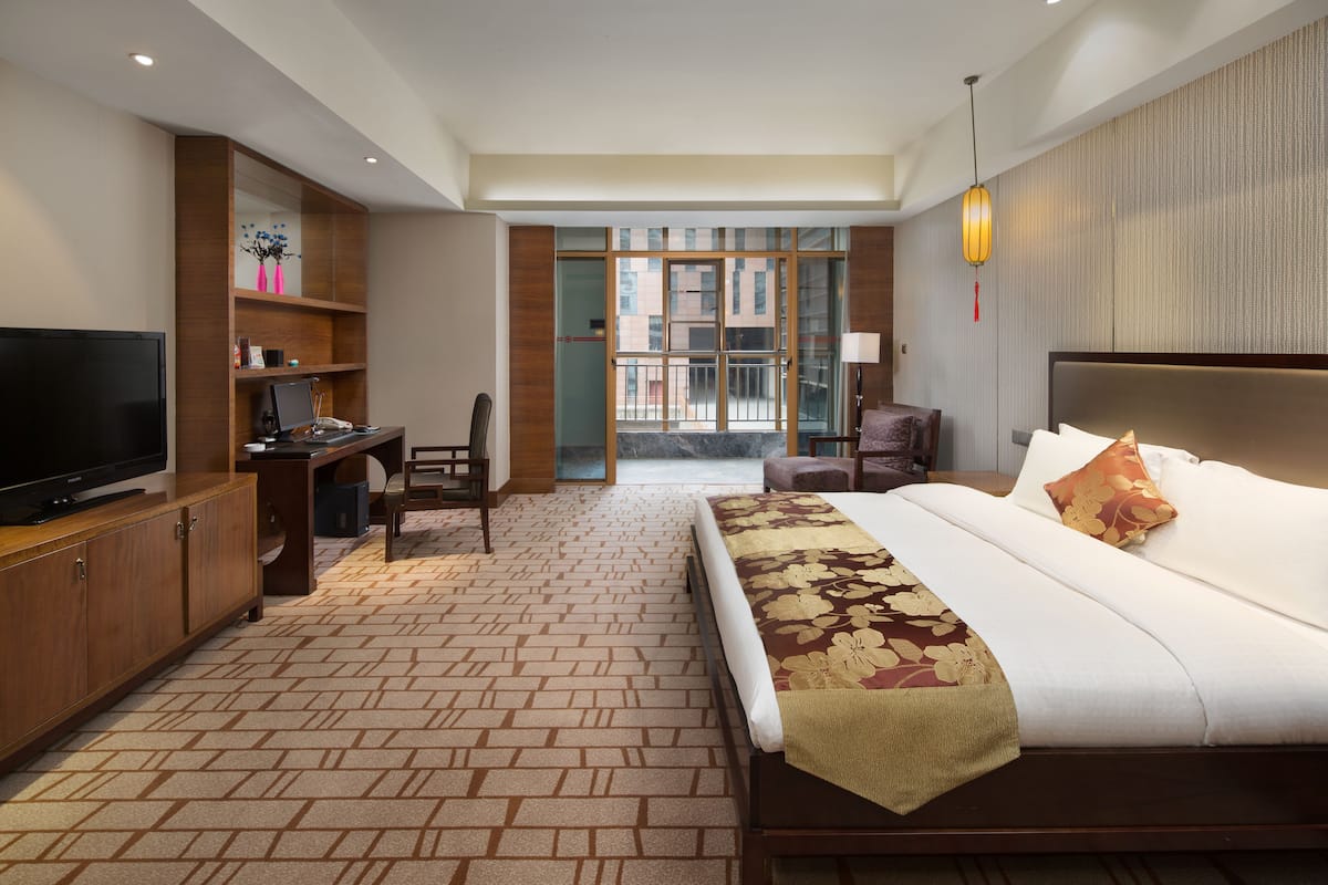 Ein Hotelzimmer mit Bett, Schreibtisch, Fernseher und Blick ins Freie.