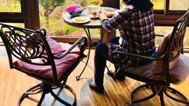A person sitting at a table with a view of mountains through large windows. - Margaret Garden Villa (Ren'ai)