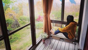 A person sitting on a bench by a window with a view of a garden. - Margaret Garden Villa (Ren'ai)