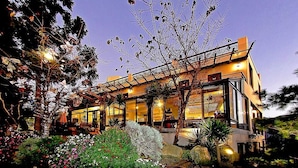 A modern two-story house with a balcony, surrounded by lush gardens and trees. - Margaret Garden Villa (Ren'ai)