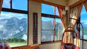 A room with a bed, a red chair, and large windows offering a mountain view. - Margaret Garden Villa (Ren'ai)