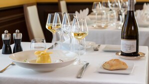 A dining table set with wine glasses, a bottle of wine, a plate with a dessert, and a croissant. - Hotel Restaurant Famille Bourgeois (Sancerre)