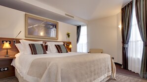 A hotel room with a large bed, a headboard with a mirror, a bedside table with a lamp, and a window with curtains. - Hotel Restaurant Famille Bourgeois (Sancerre)