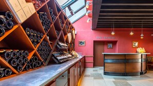 A wine cellar with wooden racks and a counter displaying wine bottles. - Hotel Restaurant Famille Bourgeois (Sancerre)