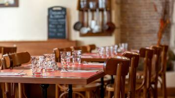 Un restaurant avec des tables et des chaises en bois, un menu écrit à la craie et des ustensiles de cuisine accrochés au mur.