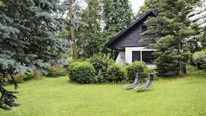 A modern house with a dark roof, surrounded by lush greenery and a well-maintained lawn. - Ferienhaus Drebach (Drebach)