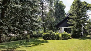 A house surrounded by a well-maintained lawn and dense trees. - Ferienhaus Drebach (Drebach)