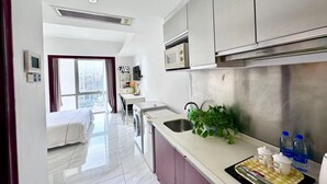 A modern hotel room with a bed, a desk, a washing machine, a sink, and a microwave. - Guangzhou Damei Apartment (Guangzhou)