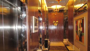 A hallway with a checkered floor, a wooden door with a golden emblem, and a chandelier. - Guangzhou Damei Apartment (Guangzhou)