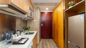 A compact kitchen with a sink, stove, and a refrigerator. - Guangzhou Damei Apartment (Guangzhou)
