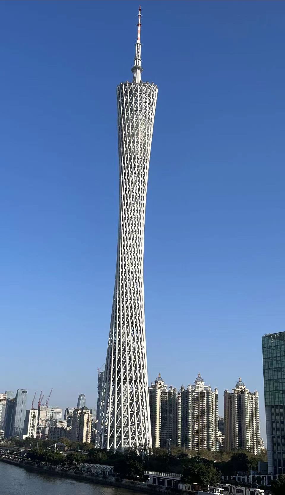 A tall, uniquely designed tower with a distinctive twisted structure, surrounded by modern high-rise buildings.