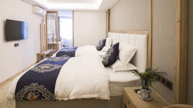 A bedroom with a bed, bedside tables, a TV, and a window.