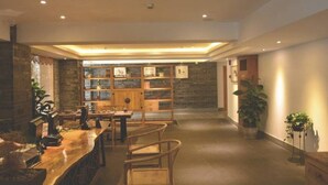 A spacious, well-lit interior with a long wooden counter, seating area, and a bookshelf.