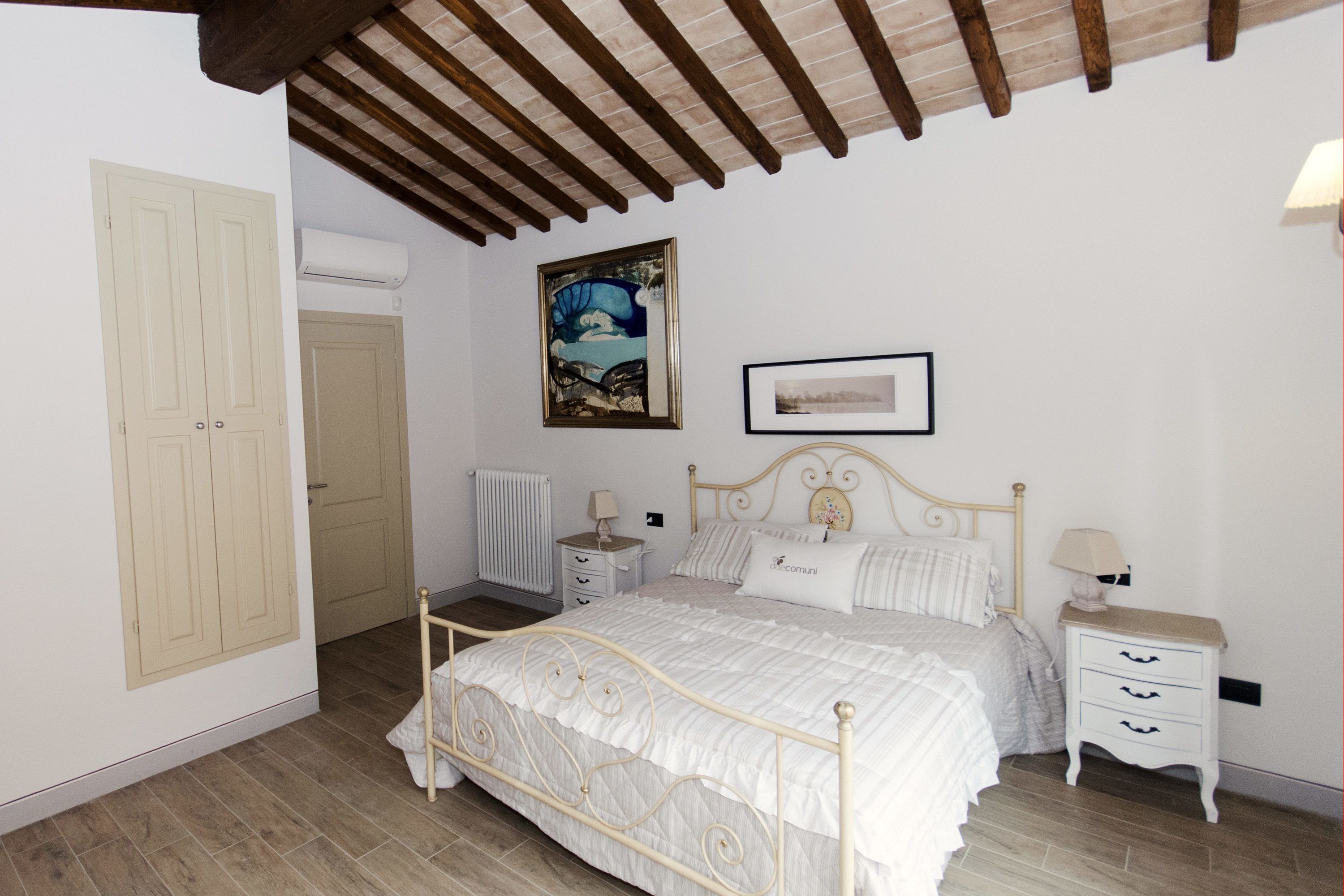 A bedroom with a bed, bedside tables, a wardrobe, and a ceiling with wooden beams.