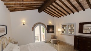 Ein Schlafzimmer mit einem Bett, einem Sessel, einer Kommode und einem Fenster mit Aussicht.