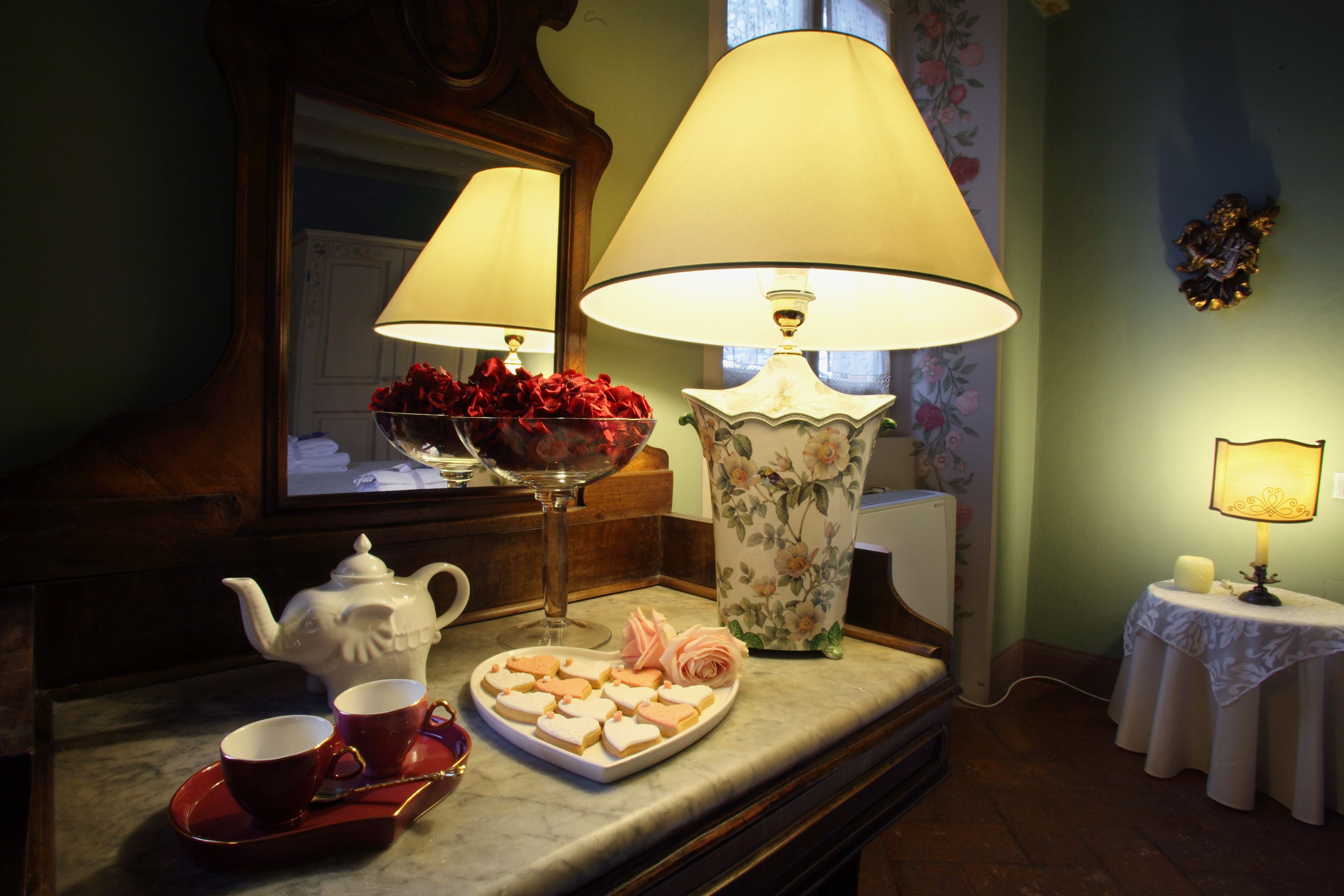 Ein Esstisch mit Teekanne, Tassen, einem Teller mit Essen und zwei Lampen.