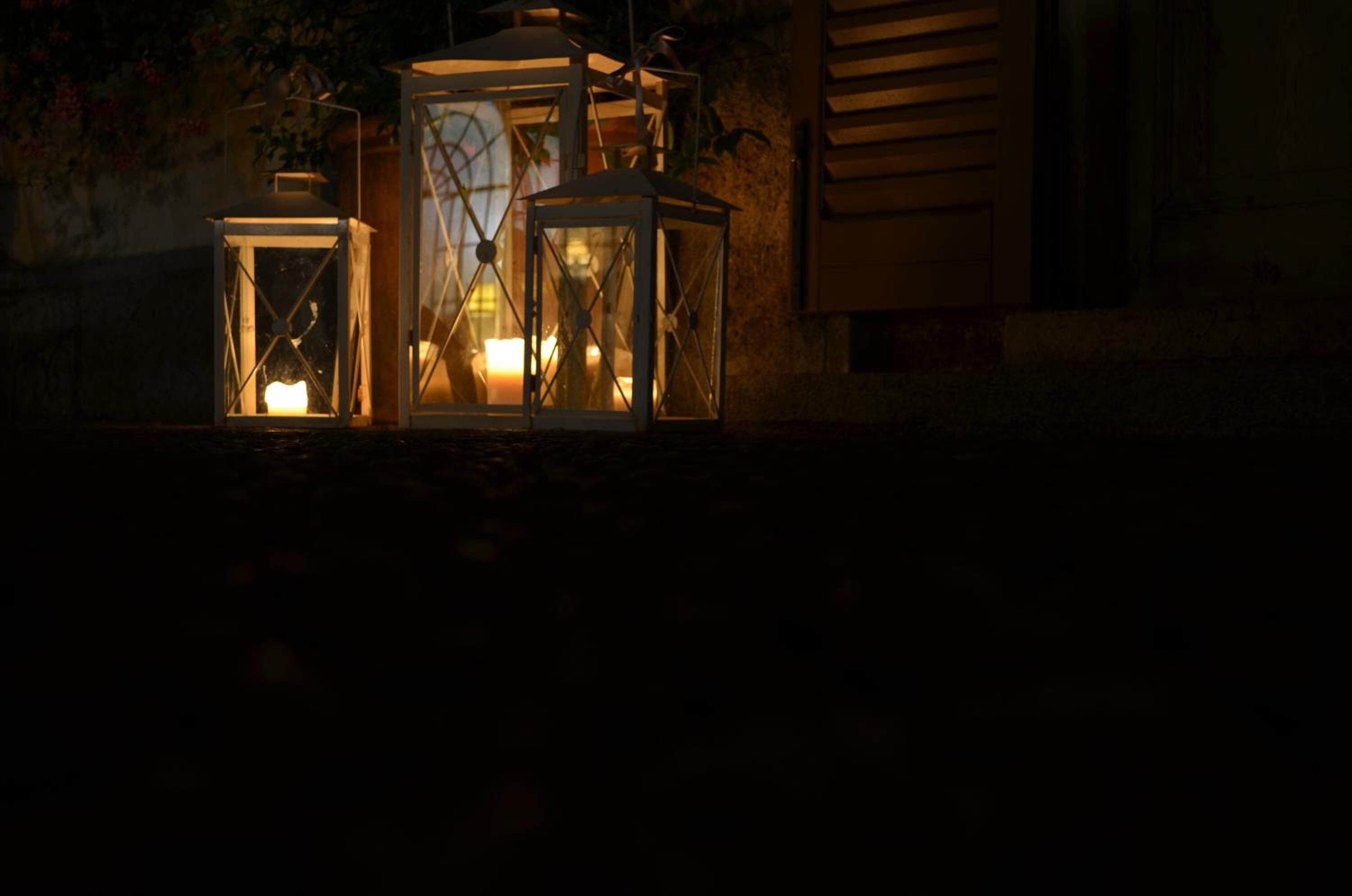 Tres faroles iluminados en un entorno oscuro, posiblemente al aire libre de noche.