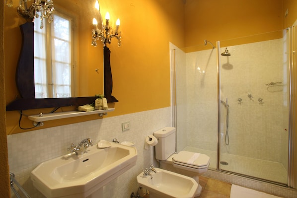A bathroom with two sinks, a toilet, and a glass-enclosed shower.