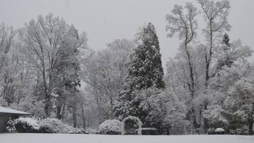 A snow-covered landscape with trees and a gazebo.