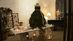 A Christmas-themed display with a mannequin in a tree-like dress, surrounded by candles, lanterns, and festive decorations. - Villa Valentina (Tradate)